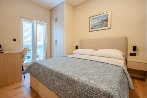 a bedroom with a large bed and two windows at Guest house AnĐela in Neum