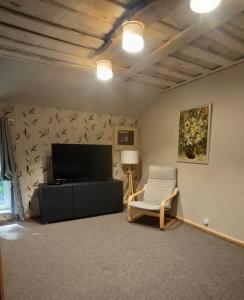a living room with a flat screen tv and a chair at Melleņu ligzda in Puršēni