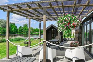 a pergola with white chairs and flowers on a deck at ''Zunds'' Camping house in Riga
