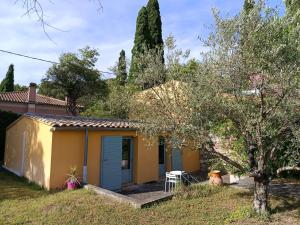 a yellow house with a blue door in a yard at Maisonnette dans un parc du 18ème in Aix-en-Provence