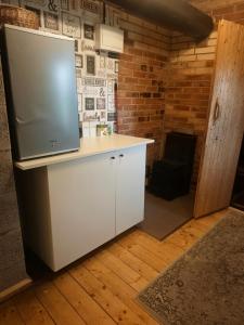 a kitchen with a counter with a refrigerator and a chair at Melleņu ligzda in Puršēni