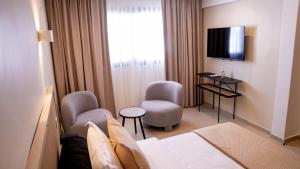 ein Hotelzimmer mit einem Bett, zwei Stühlen und einem Fernseher in der Unterkunft Kadiss Hotel in Dakar