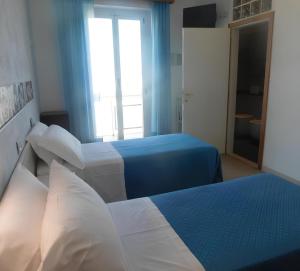 a hotel room with two beds and a window at Hotel Dolores in Rimini