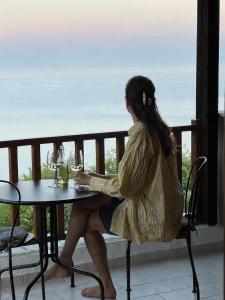 a woman sitting at a table with glasses of wine at Om Living Pelion in Agios Dimitrios