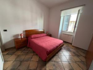 a bedroom with a red bed and a window at Bouganville House in Nettuno