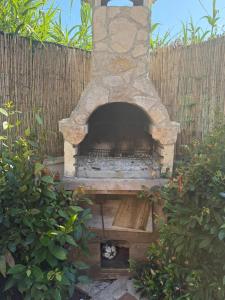 a stone oven in a backyard with a fence at Bouganville House in Nettuno