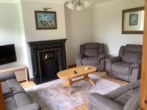 a living room with couches and a table and a fireplace at Kilmurry heights in Kenmare