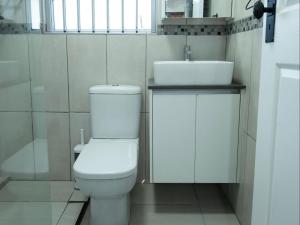 a bathroom with a white toilet and a sink at Oliverio Seaside Living in Sedgefield +4 photos