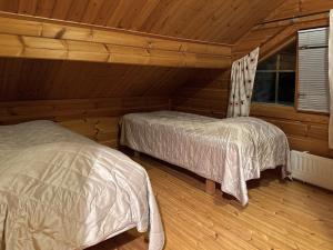two beds in a room with wooden walls at Par 10 in Tahkovuori