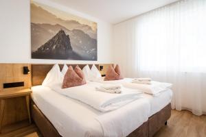 two beds in a hotel room with a picture on the wall at Alpenstolz Damüls Haus 1 - Stilvoll urlauben in den Bergen in Damuls