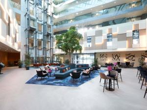 a lobby with chairs and tables in a building at Mercure Geneva Airport in Geneva
