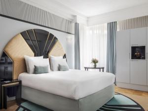 a bedroom with a large bed with a large headboard at The 1932 Hotel & Spa Cap d'Antibes - MGallery Collection in Juan-les-Pins