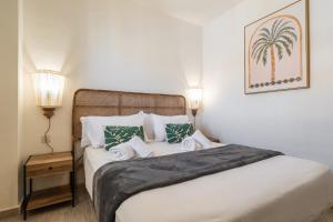 a bedroom with a bed with two lamps and a palm tree picture at Las Dunas by Ĥ in Isla del Moral +90 photos