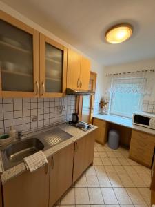 a kitchen with wooden cabinets and a sink at Apartman Nina in Kvačany +1 photo