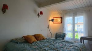 a bedroom with a bed and a lamp and a window at Maison Barbâtre in Barbâtre