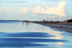 two people walking on the beach in the water at Vila hangloose Jericoacoara in Acaraú