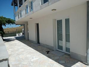 a white building with doors and a patio at Apartmani Lalu in Rtina +2 photos