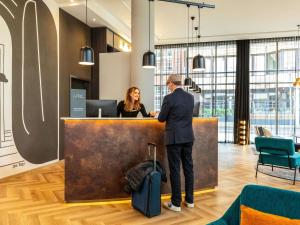 a man and a woman standing at a counter at ibis Styles Bielefeld City in Bielefeld