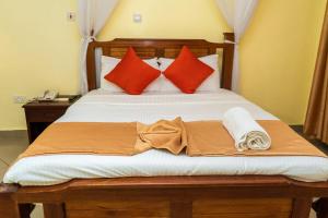 a bed with red and orange pillows and a blanket at Grand Forty Garden Ltd in Kisumu