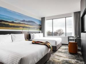 a hotel room with two beds and a large window at Novotel Devonport in Devonport