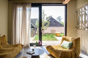 a living room with two chairs and a large window at Walingsuites in Holwerd