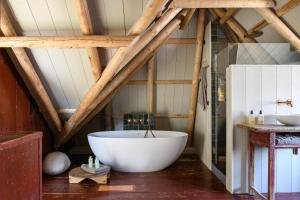 a bathroom with a large white tub in a attic at Walingsuites in Holwerd +34 photos