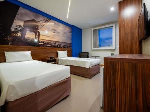 a hotel room with two beds and a painting on the wall at Ibis Styles Belém Hangar in Belém