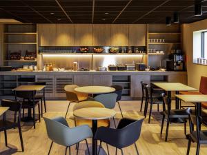 a restaurant with tables and chairs and a kitchen at ibis Brussels Groot Bijgaarden in Groot-Bijgaarden