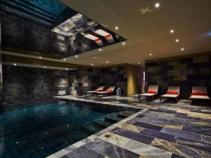 a swimming pool in a hotel with benches and chairs at La Licorne Hotel & Spa Troyes - MGallery Collection in Troyes