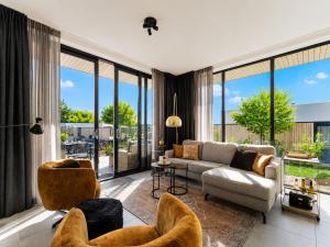 a living room with a couch and chairs and large windows at Harderwold Villa - 412 in Zeewolde