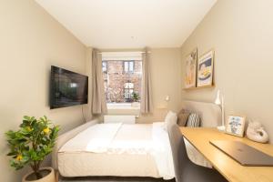 a bedroom with a bed and a desk with a laptop at Kongens Gate Rooms in Kristiansand