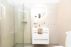 a white bathroom with a shower and a sink at Kongens Gate Rooms in Kristiansand +71 photos
