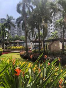 a park with palm trees and flowers in front of a building at Accommodating Place in Manila