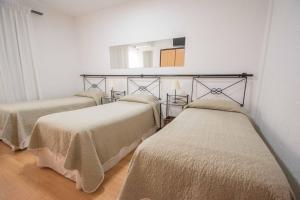 three beds in a room with a mirror at Hotel Marbella in Punta del Este