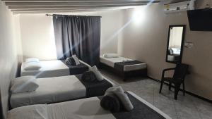 a hotel room with two beds and a mirror at Hotel Distrito Unicentro in Medellín