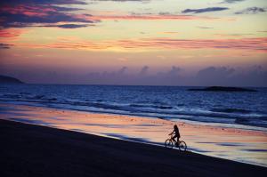 a person riding a bike on the beach at sunset at Vila hangloose vista da lagoa in Acaraú +40 photos