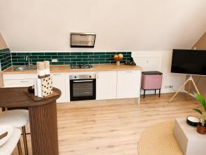a kitchen with white cabinets and green tile at Wonenmeteenknipoog Groningerweg 23D in Peize
