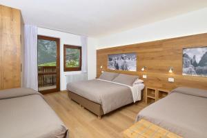 ein Hotelzimmer mit zwei Betten und einem Schreibtisch in der Unterkunft Hotel Cima Tosa in San Lorenzo in Banale