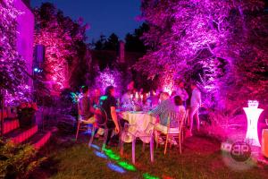 a group of people sitting at a table in a garden with purple lights at Relax in Style Boutique Hotel in Braşov