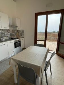 a kitchen with a table and chairs and a kitchen with a window at Aria Case Vacanze - Frumento in Favignana