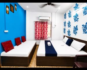 two beds in a room with blue and red at Trip Kashi Guest House in Varanasi