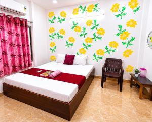 a bedroom with a bed and a chair and flowers on the wall at Trip Kashi Guest House in Varanasi