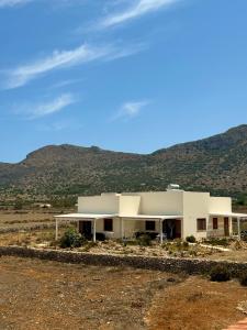 a large white building with mountains in the background at Aria Case Vacanze - Frumento in Favignana