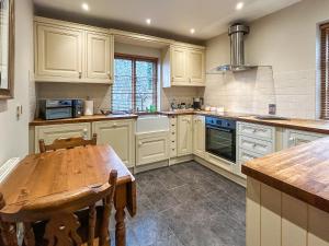 a kitchen with white cabinets and a wooden table at Ye Olde Stone House in Sutton Coldfield