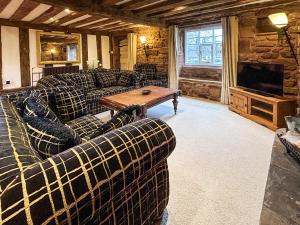 a living room with couches and a table and a tv at Ye Olde Stone House in Sutton Coldfield