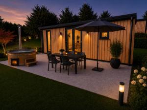 a patio with a table and an umbrella and a tub at Hassberge Chalets in Kirchlauter