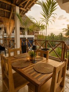 a wooden table with chairs on a balcony with palm trees at Smile Boutique Beach hotel in Nungwi