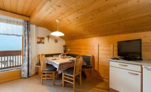 a dining room with a table with chairs and a television at Lüch de Tor in San Martino in Badia