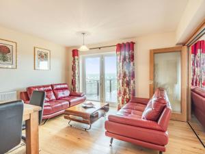 a living room with red leather furniture and a large window at Paradise in Cinderford