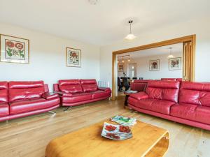 a living room with red leather couches and a table at Paradise in Cinderford
